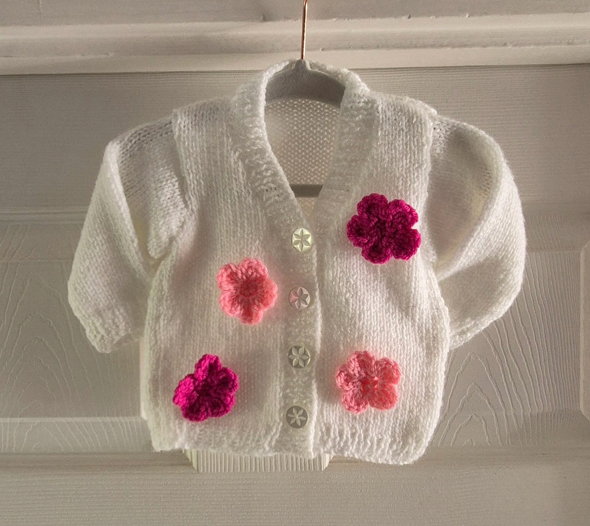 Knitted white cardigan, adorned with crochet flowers