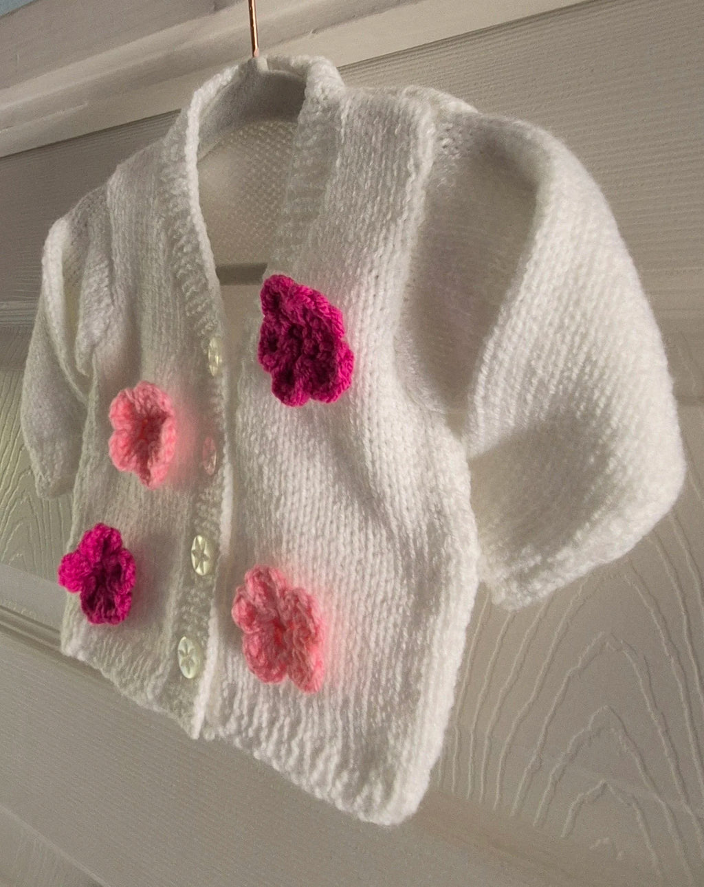 Knitted white cardigan, adorned with crochet flowers