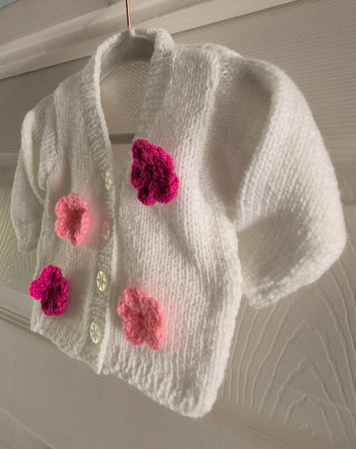 Knitted white cardigan, adorned with crochet flowers