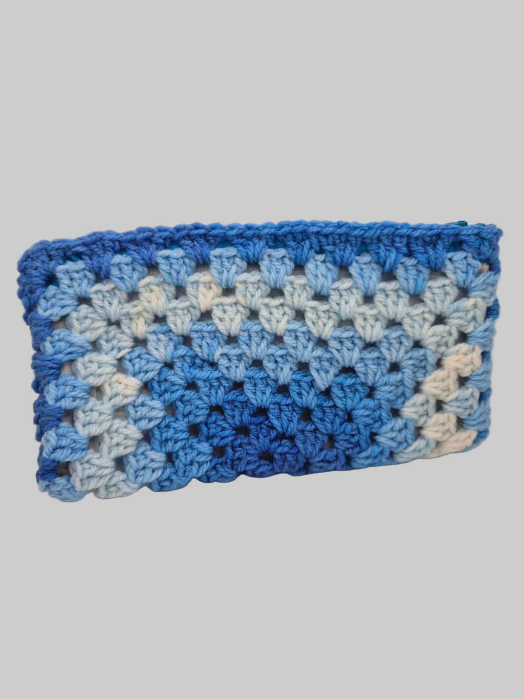 A handmade crocheted clutch bag in a blue and white chevron pattern, shown against a plain light gray background.